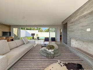 Sala de estar moderna com grandes portas de vidro e área externa.