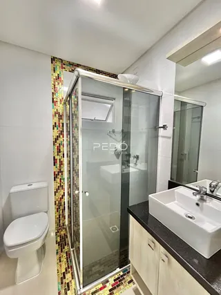 Foto de um banheiro com box de vidro e piso de mosaico colorido.