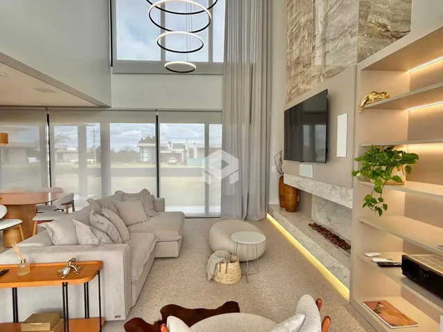 Sala de estar moderna com grandes janelas e decoração clara.