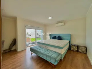 Quarto com cama e portas de vidro de acesso ao exterior.