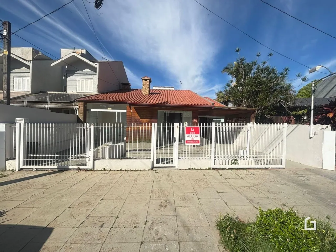 Vista externa da residência com cerca e portão branco.