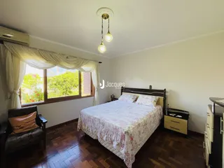 Quarto com janela e piso de madeira no imóvel em Lajeado.