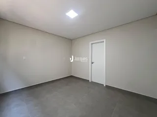 Uma sala interna com paredes brancas e piso de cerâmica cinza.