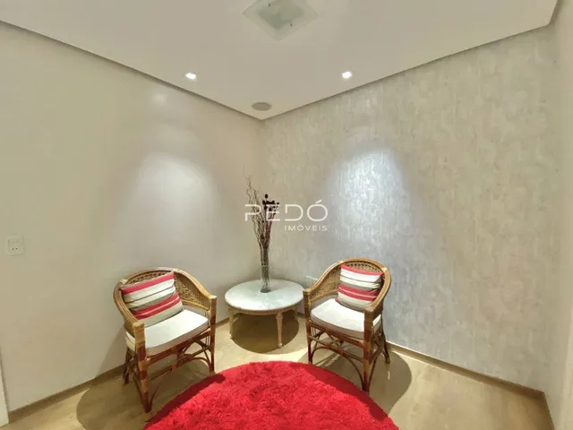 Sala de estar com duas cadeiras de vime e um tapete vermelho.