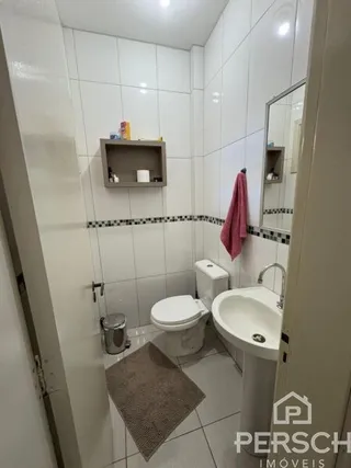 Banheiro com azulejos brancos e vaso sanitário.