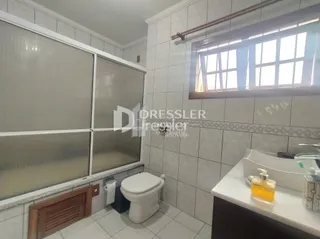 Foto de um banheiro com azulejos brancos e janela.