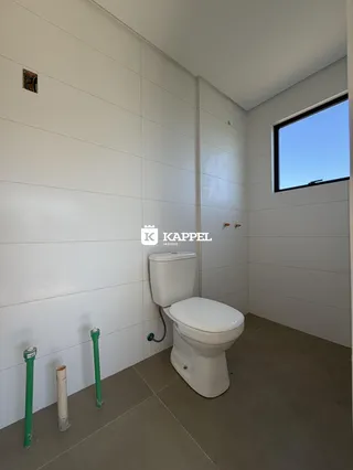 Foto interna de um banheiro com piso claro e janela.