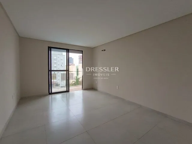 Ambiente interno de uma sala ampla com piso de cerâmica e porta de vidro.
