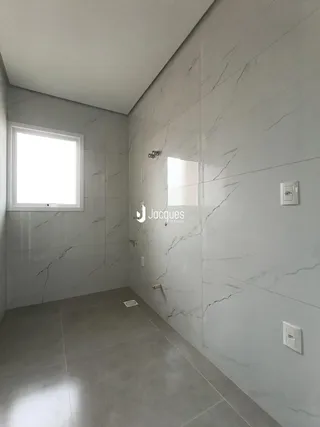 Hall de corredor com paredes em mármore claro e piso de grande formato.