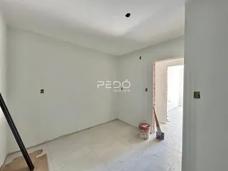 Uma área interna com paredes brancas e piso claro.