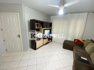 Sala de estar com sofá e móveis de madeira em ambiente claro.