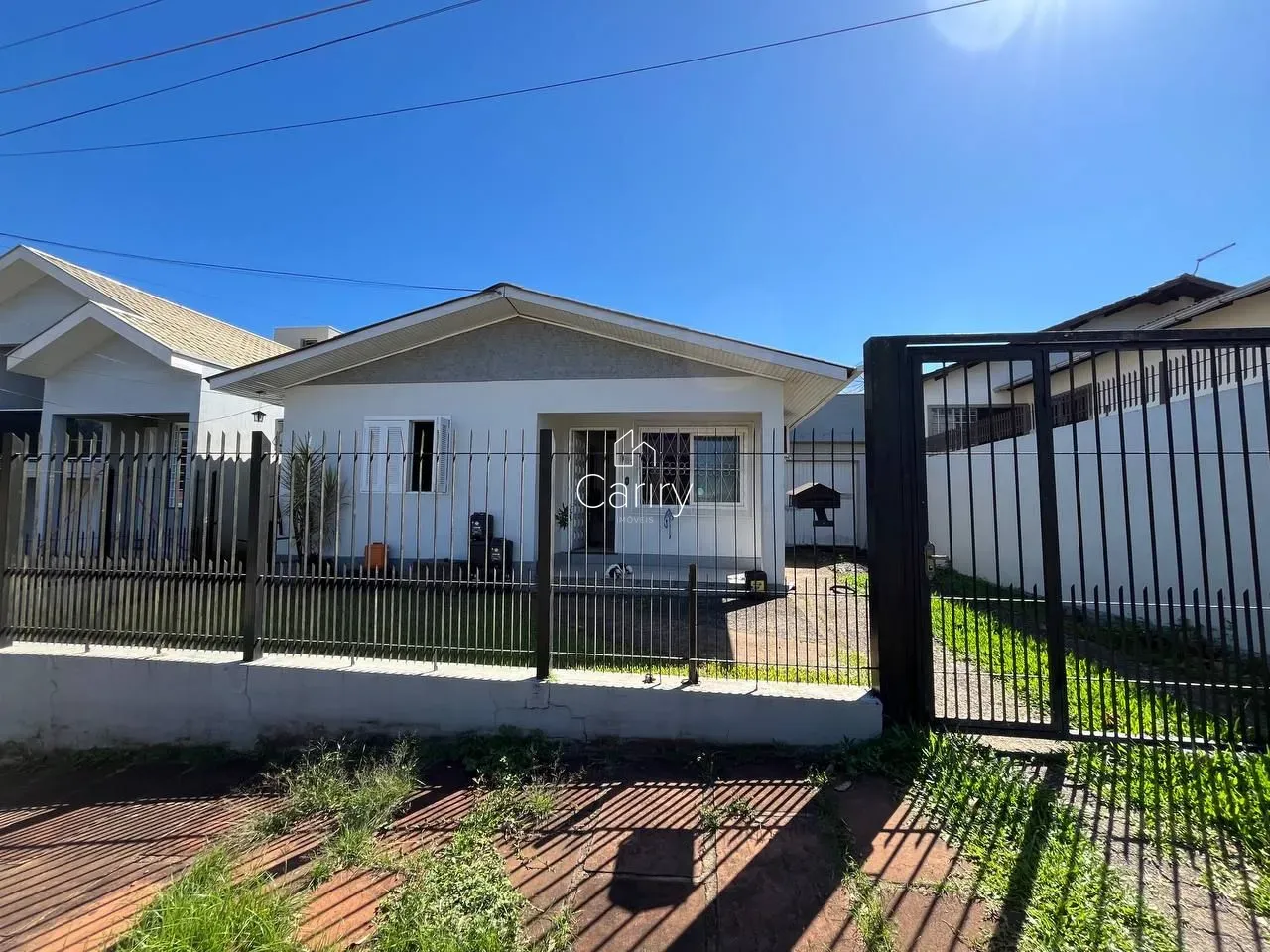Fachada de uma residência branca em Lajeado, Brasil, com cerca de metal na frente.