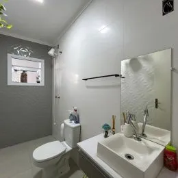 Foto de um banheiro com vaso sanitário e pia brancos.