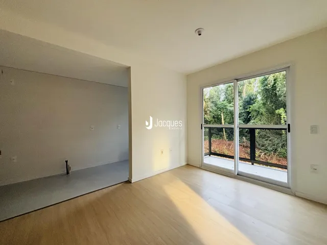 Ambiente interno com piso de madeira clara e portas de vidro que dão para o exterior.