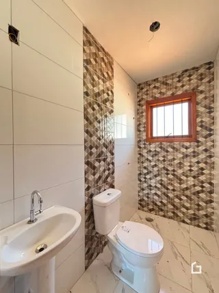 Foto de um banheiro com revestimento de azulejos marrons e brancos.