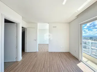 Interior de um ambiente com piso de madeira clara e paredes brancas.