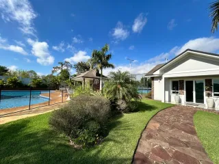 Vista externa da propriedade mostrando a piscina e o jardim.