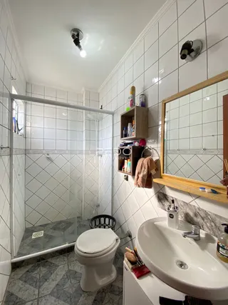 Foto de um banheiro com piso de cerâmica e azulejos brancos.