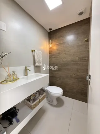Foto de um banheiro moderno com bancada branca e revestimento de parede em tons terrosos.