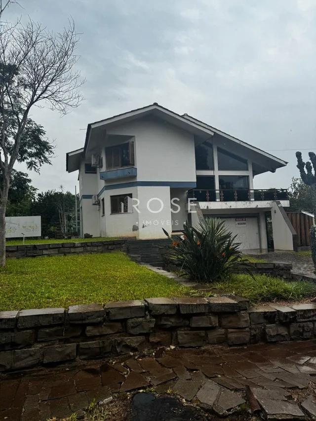 Fachada de uma residência em Lajeado, Brasil, com jardim frontal e muro de pedra.