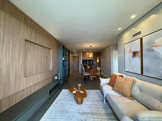 Sala de estar moderna com sofá e painel de madeira na residência.