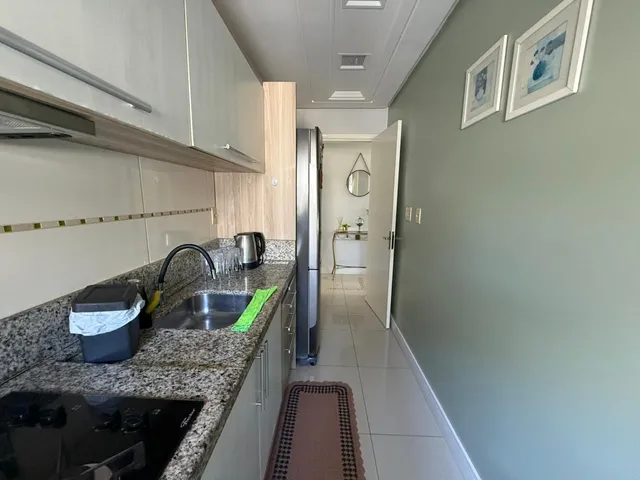 Uma foto da cozinha mostrando armários brancos e bancada de granito.