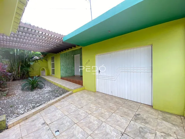 Fachada externa de uma residência em Lajeado, Brasil, com garagem branca e revestimento verde.