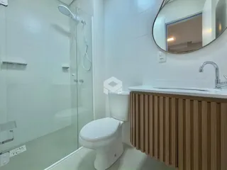 Banheiro com box de vidro e bancada de madeira no imóvel.