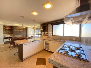 Vista interna de uma cozinha com armários brancos e bancadas de granito.