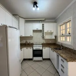 Uma foto de uma cozinha com armários brancos e bancadas.