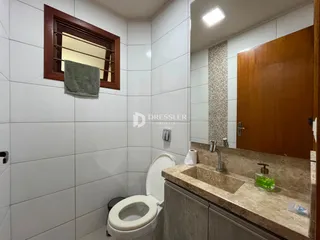 Foto interna de um banheiro com revestimento cerâmico branco.