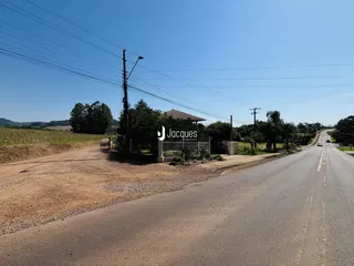 Vista da propriedade com estrada de terra e cerca de entrada.