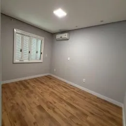 Foto de um cômodo interno com piso de madeira clara e janela.