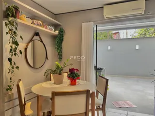 Sala de jantar com mesa de madeira e vista para o exterior.