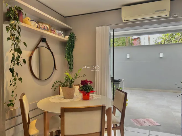 Sala de jantar com mesa de madeira e vista para o exterior.