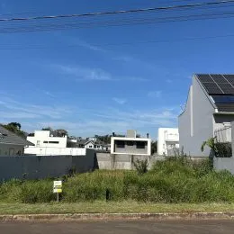 Fachada externa de uma residência com painéis solares sob um céu azul.
