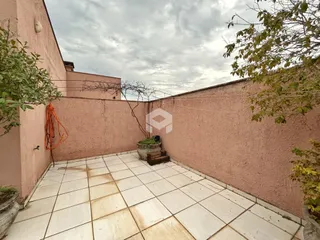 Vista externa de um pátio com piso de cerâmica e muro de alvenaria.