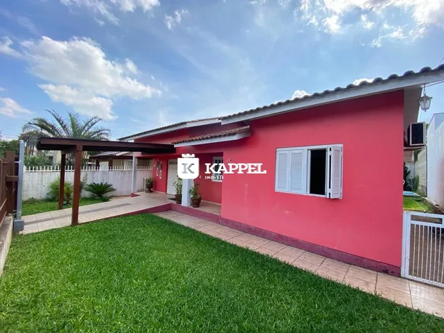 Fachada de uma casa vermelha com jardim verde em Lajeado, Brasil.