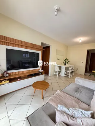 Sala de estar com sofá, mesa de centro e painel de TV em um ambiente claro.