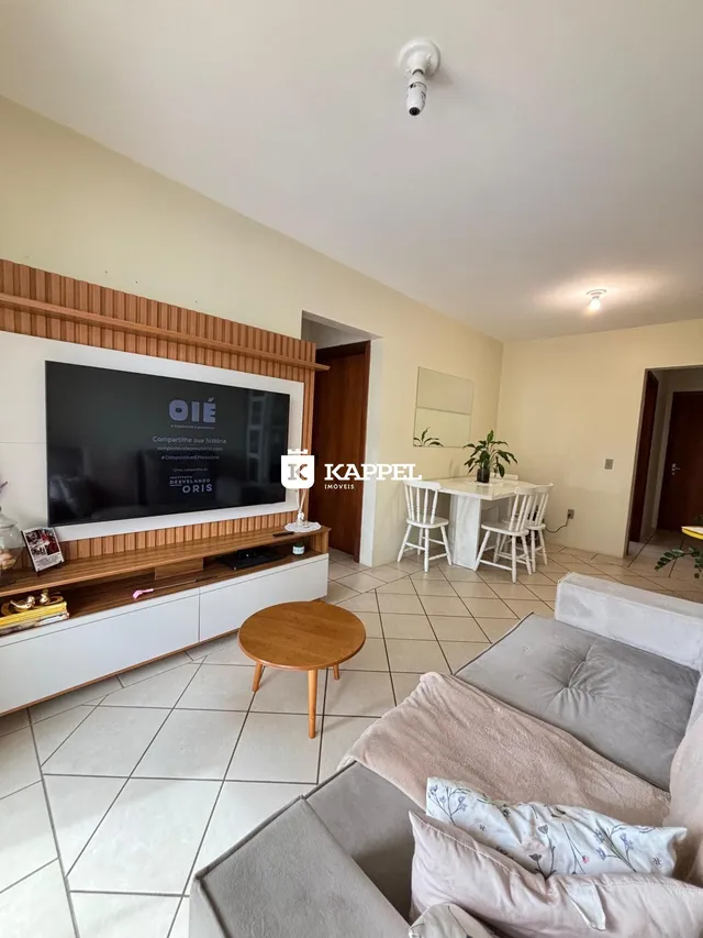 Sala de estar com sofá, mesa de centro e painel de TV em um ambiente claro.
