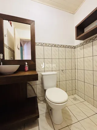 Foto de um banheiro com piso de cerâmica e revestimento de azulejos nas paredes.
