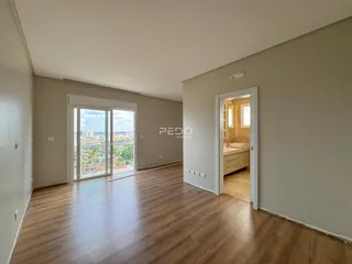 Sala de estar ampla com piso de madeira clara e vista da cidade.