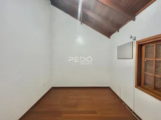 Imagem de um cômodo interno com piso de madeira e teto inclinado.