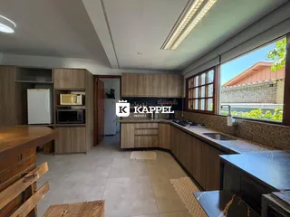 Cozinha com armários de madeira e bancada clara em um imóvel no Brasil.