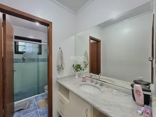 Banheiro com bancada de mármore e espelho no interior de uma residência.