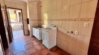 Banheiro com revestimento de azulejos brancos e piso de terracota.