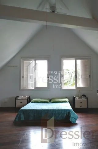 Quarto com cama e janelas em uma residência.