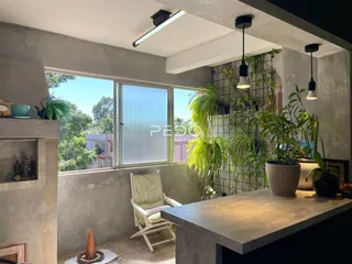 Vista interna de uma área com grande janela e vegetação.