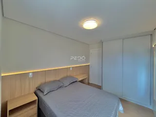 Quarto com cabeceira de madeira e armários brancos.