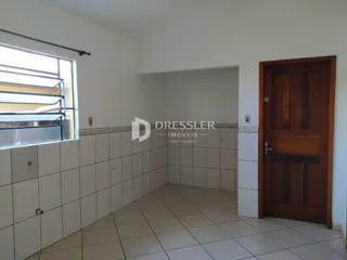 Vista interna de uma sala com piso de cerâmica e uma porta de madeira.